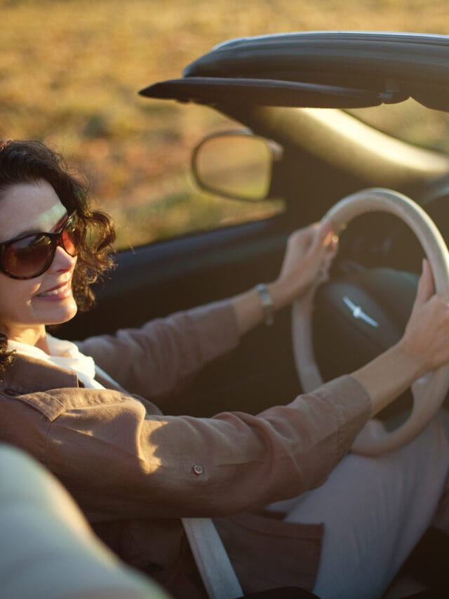Woman driving convertible automobile on a sunny day in the fall