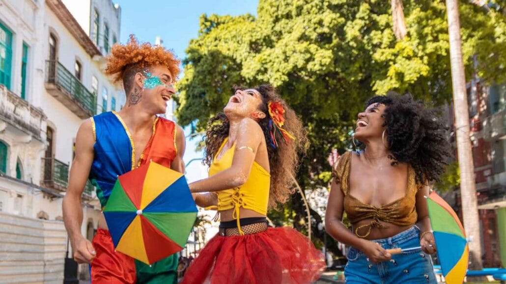 Grupo de pessoas fantasiadas e maquiadas celebra o Carnaval ao ar livre