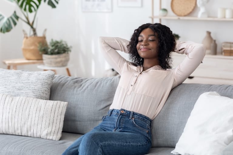 Mulher encostada no sofá da sala relaxando em um ambiente acusticamente tranquilo