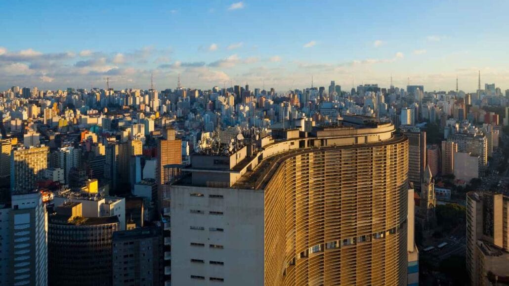 Vista panorâmica de edifícios de São Paulo com grande quantidade de arranha-céus e prédios sob céu azul.