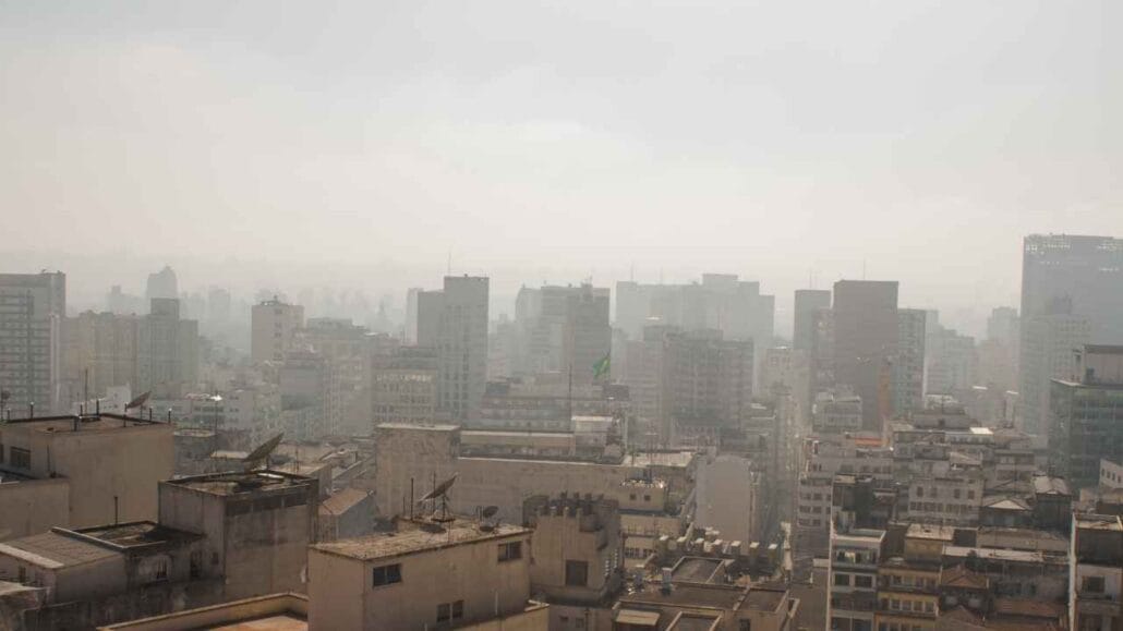 Paisagem urbana de São Paulo com prédios parcialmente encobertos por névoa densa na atmosfera.