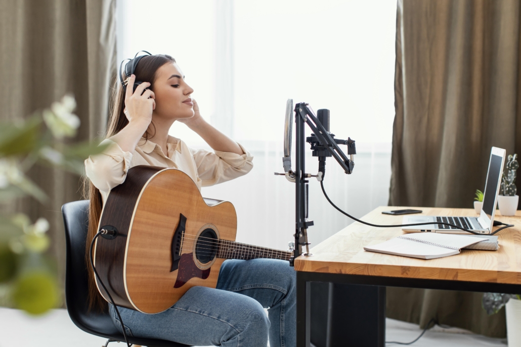 Mulher tocando violão e usando fones de ouvido em um home estúdio com janela antirruído da AtenuaSom, ambiente ideal para compor músicas com concentração e criatividade.