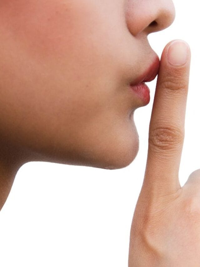 pessoa segurando o dedo em frente ao lábios em símbolo de silencio