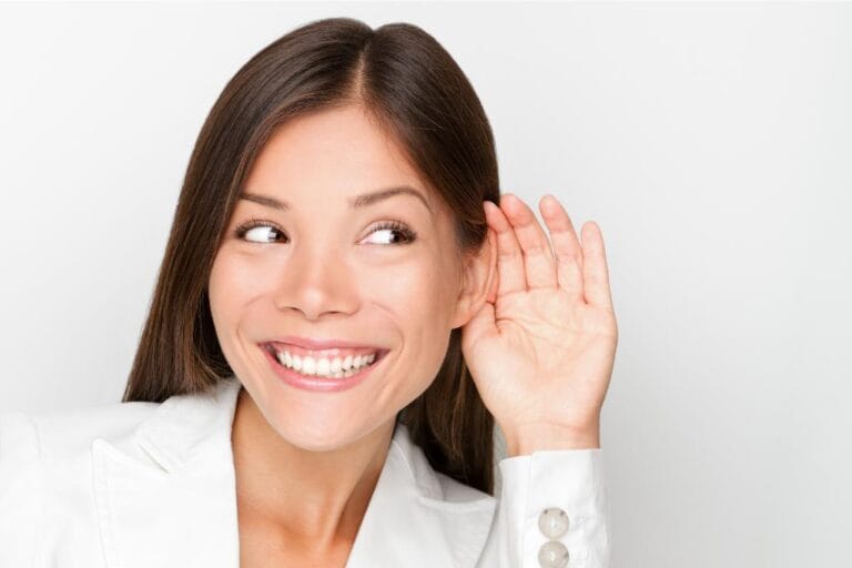 mulher sorrindo com a mão no ouvindo demonstrando que está com boa audição
