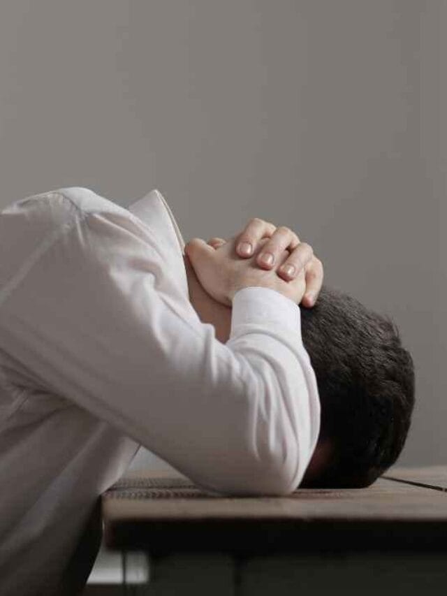 Pessoa com a cabeça apoiada na mesa demonstrando estresse extremo causado pela exposição a altos níveis de ruído e decibéis no ambiente.