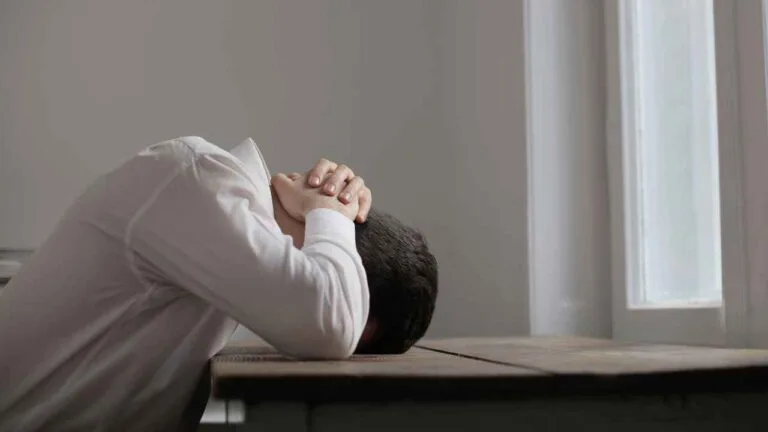 Pessoa com a cabeça apoiada na mesa demonstrando estresse extremo causado pela exposição a altos níveis de ruído e decibéis no ambiente.