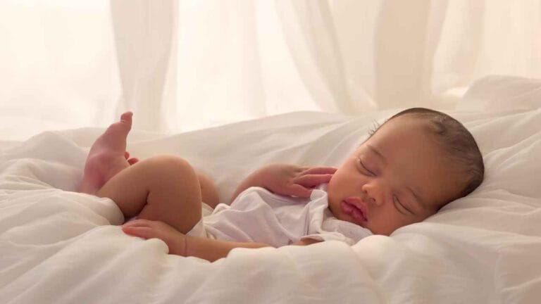 Bebê dormindo tranquilamente deitado em cama com lençóis brancos e iluminação suave perto de uma janela antirruido