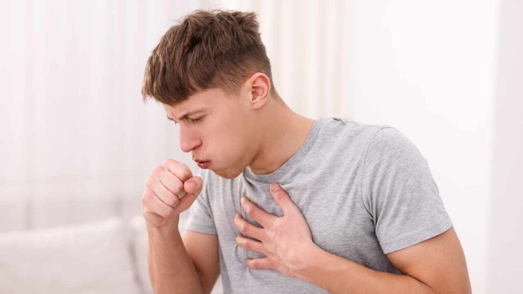 Homem com expressão de mal-estar, tossindo e segurando o peito