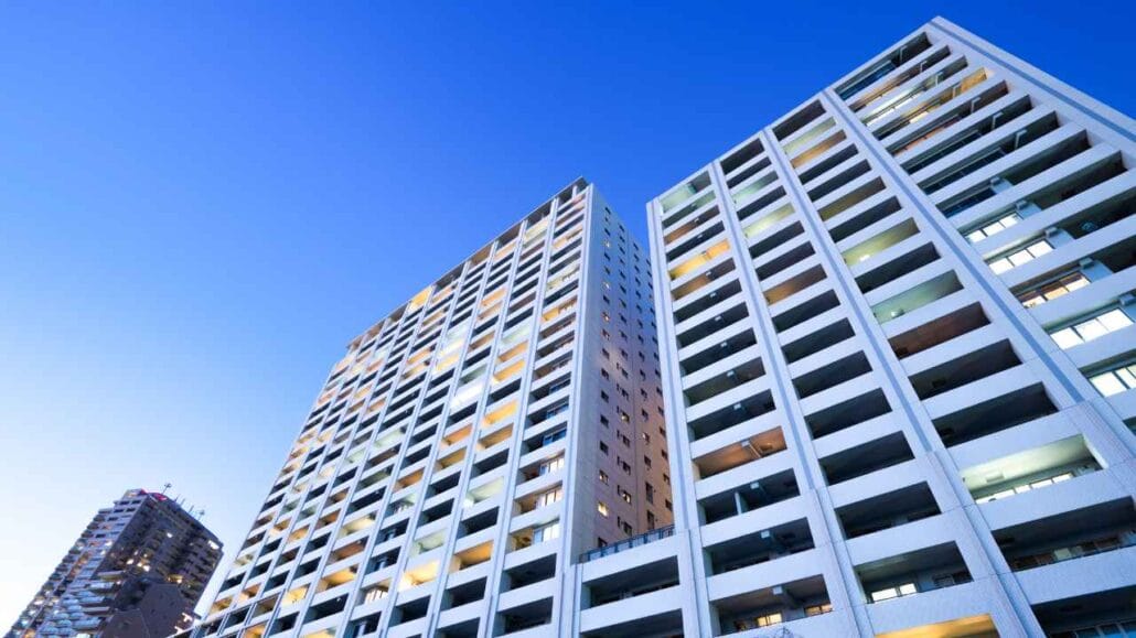 Conjunto de edifícios altos com fachada moderna e diversas sacadas, visto de baixo contra o céu azul.