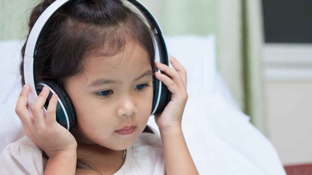 riança usando fones de ouvido grandes enquanto escuta áudio