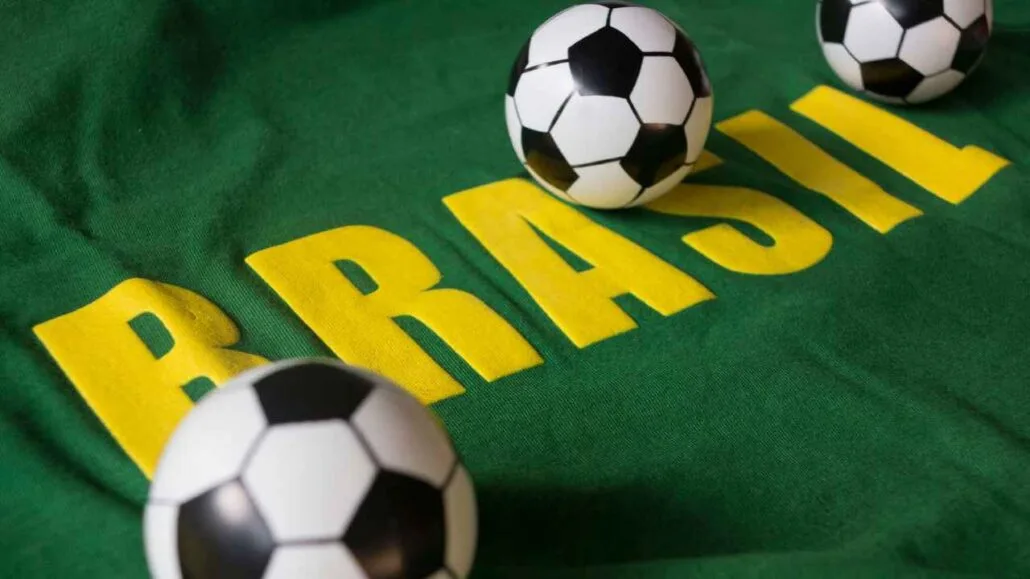 Camisa verde com a palavra “Brasil” estampada em amarelo, acompanhada por bolas de futebol